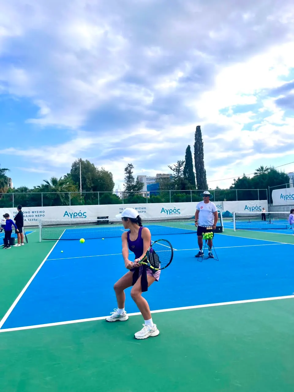 Player practising a backhand with a coach on a blue tennis court