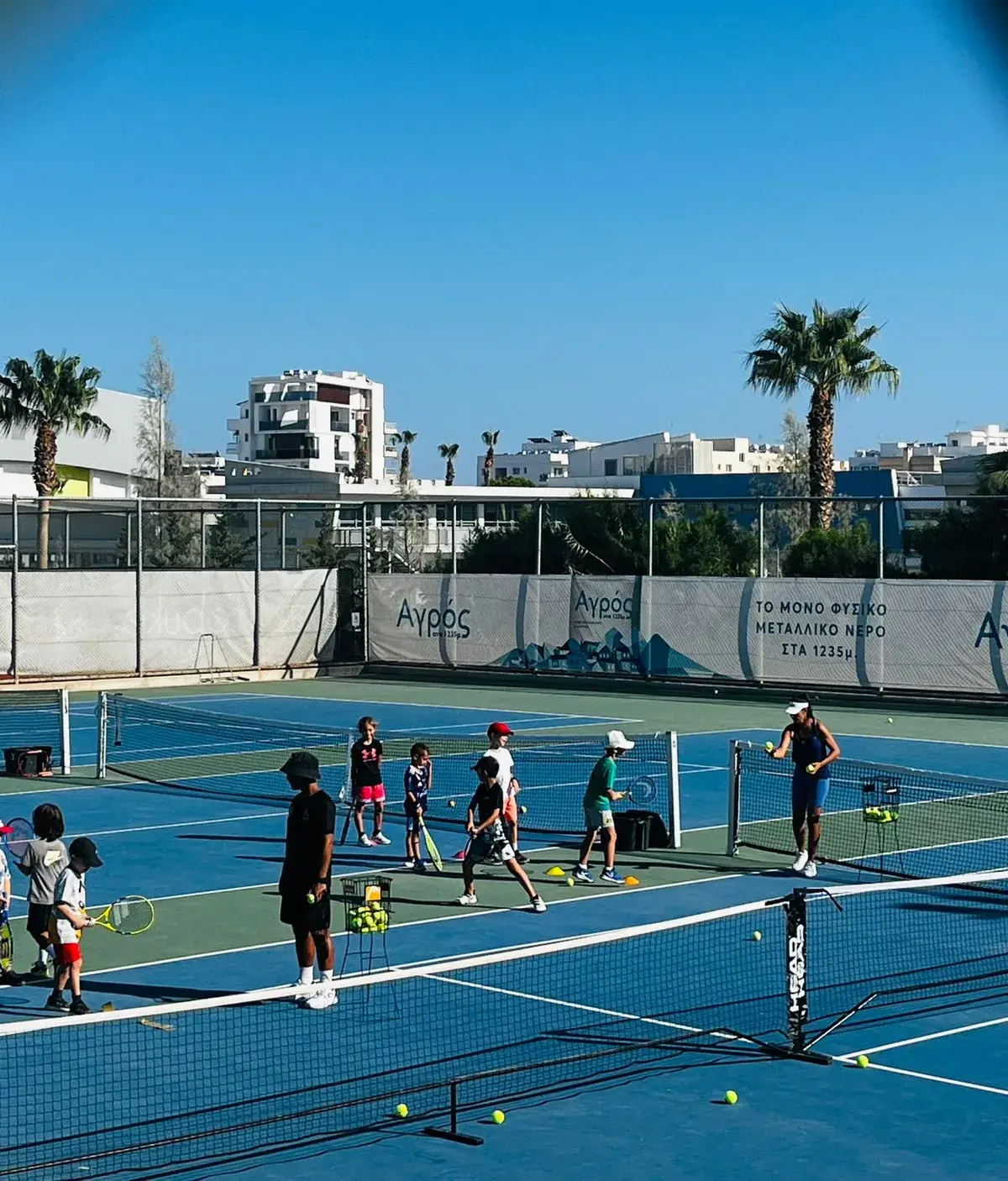 Children learning tennis together around a small net