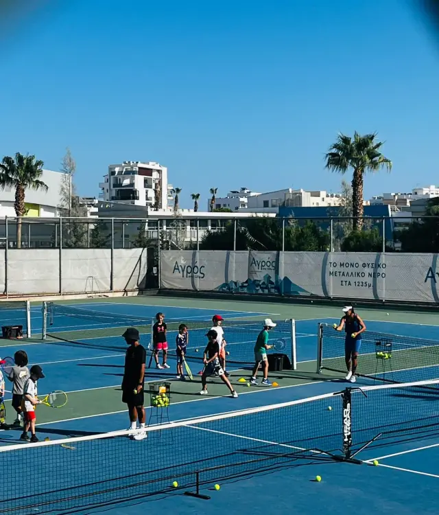 Children learning tennis with a small net and scaled equipment