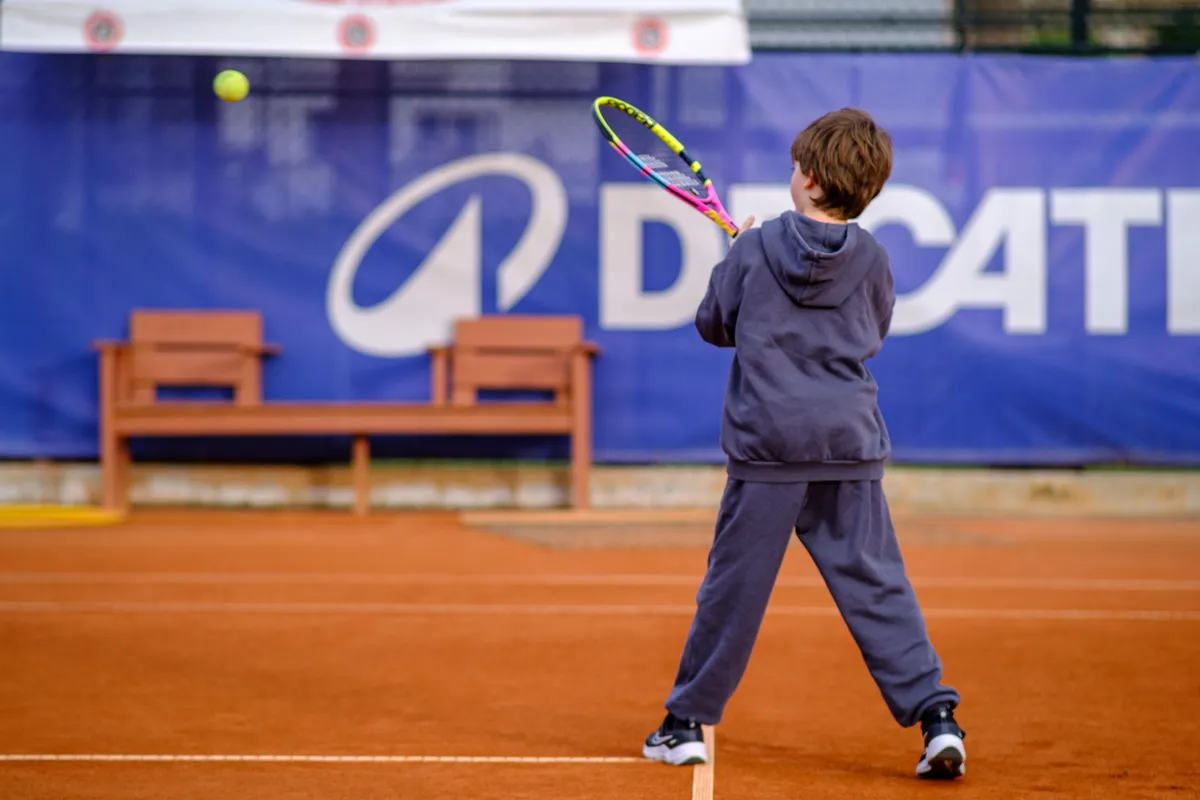 A junior player preparing a backhand on a clay court