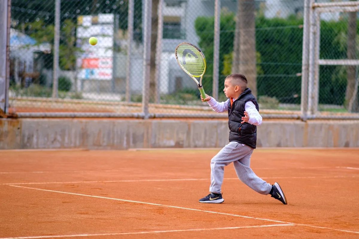 A young player reaching for a forehand on a clay court
